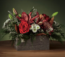  Floral arrangement with red roses, white flowers, and greenery in a wooden box on a dark background.